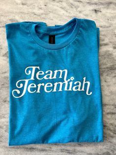 anyone else obsessed with The Summer I Turned Pretty?! choose your team! I'm a 50/50 split but this is a TEAM JEREMIAH SHIRT ...these tees are soft and cozy and ship quickly 🥰 These are unisex boyfriend fit so size down for a snugger fit. As with all vinyl:  Make sure to wash inside out  on cool water. Dry on low. Do not iron. Blue Top With Name Print For Game Day, Blue Tops With Name Print For Game Day, Blue T-shirt With Name Print For Game Day, Blue Name Print T-shirt For Game Day, Pre-shrunk Cotton Tops For Team Events, Cotton Tops With Name Print For Team Events, Casual Blue Tops For Team Events, Blue T-shirt With Name Print For Fan Merchandise, Blue Tops With Letter Print For Team Events