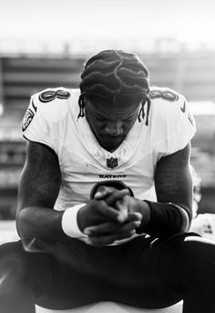 a man sitting on top of a bench looking at his cell phone while wearing a football uniform