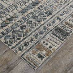 an area rug with various shapes and colors on the wooden floor in front of a window