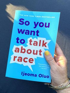 a person holding up a book that says so you want to talk about race