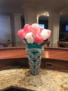 a vase filled with pink and white flowers on top of a marble counter next to a dining room table