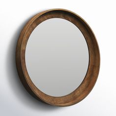 a round mirror hanging on the wall next to a white wall with a wooden frame