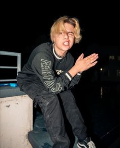 a young man riding a skateboard on top of a cement wall at night time