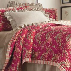 a bed with red and white bedspread, pillows and blankets on top of it