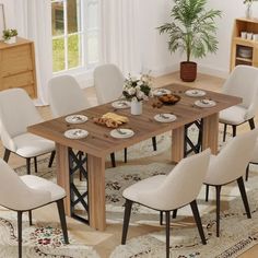 a dining room table with white chairs and plates on the wooden table in front of a potted plant