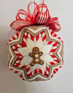 a christmas ornament with a gingerbread man on it's face and candy canes in the shape of a snowflake