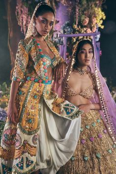 Editor's Note Featuring an ivory raw silk dhoti embroidered with gold metal embellishments, 3D butterflies, glass cut beads and precious crystals, appliqued in yellow, blue, teal and lilac silks. It is paired with an appliquéd half-sleeved 3 coloured jacket with gold tassels and multicolour glass cut crystals. This look is completed with a light pink tulle dupatta embroidered with reflective stones, sequins and precious crystals. Color : Ivory, light pink Fabric: Raw silk, tulle Sleeve type: Jac Indian Outfits Lehenga, Metal Embellishments, Bollywood Outfits, Tulle Sleeves, Fashion Designing, Indian Bridal Fashion, 3d Butterflies, Pink Tulle, Butterfly Sleeves