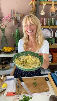 a woman holding up a plate of food in front of a table full of plates and utensils