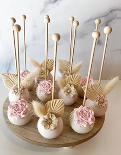 there are some cake pops with pink flowers on them and gold sticks sticking out of them