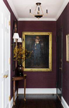 a hallway with a painting on the wall and a table in front of it next to a lamp