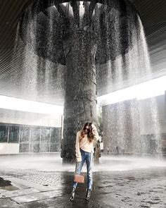 a woman standing in front of a fountain with water shooting from her hands and head