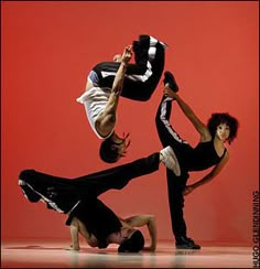 three people doing different poses in front of a red wall