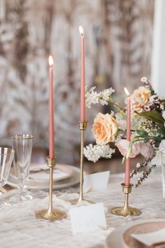 the candles are lit on the table with flowers