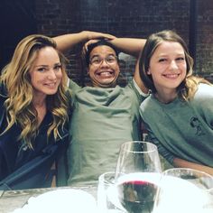 three people sitting at a table with wine glasses