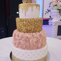 a three tiered cake with gold and pink icing on it's side