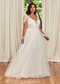 a woman standing in front of a window wearing a wedding dress