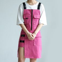 a woman in pink overalls and white shirt standing with her hands on her hips