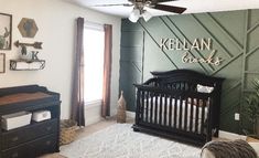 a baby's room with green walls and white rugs on the floor in front of a black crib