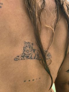 a man with long hair has a tiger tattoo on his chest