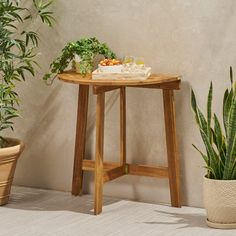 two potted plants sitting next to each other on a wooden table in front of a wall