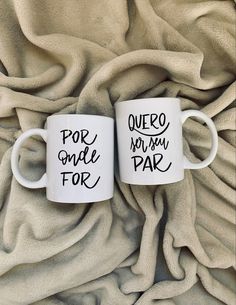 two coffee mugs sitting on top of a blanket