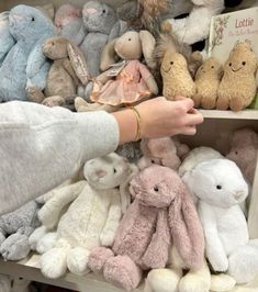 a person is picking up stuffed animals from a shelf