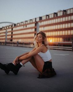 a woman is sitting on the ground in front of a building with her legs crossed