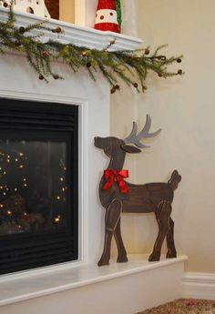 a wooden reindeer standing next to a fire place with christmas decorations on it's mantle