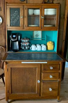 an old fashioned kitchen with teal walls and wooden cabinets, including a coffee maker