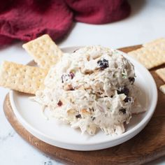 a white plate topped with crackers and a bowl of chicken salad next to it