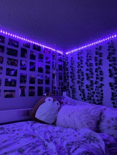 a bedroom with purple lights and stuffed animals on the wall above the bed, along with pictures hanging on the wall