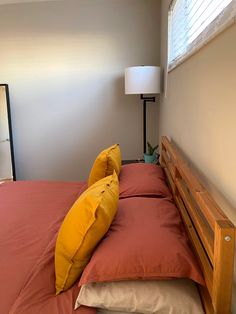 a bed with red sheets and yellow pillows