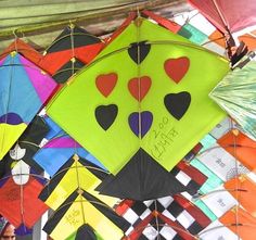 many colorful kites with hearts on them are hanging from the ceiling in a tent