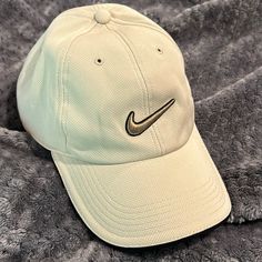 a white hat with a black nike logo on it sitting on a gray bed sheet