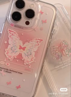 an iphone case with pink and white butterflies on it, sitting next to a pair of ear buds