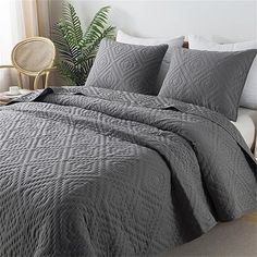 a bed with grey quilted bedspread and pillows