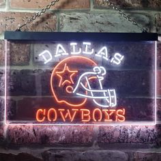 a neon sign with the word cowboys on it and a football helmet in front of a brick wall