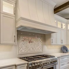 a stove top oven sitting inside of a kitchen next to white cupboards and drawers