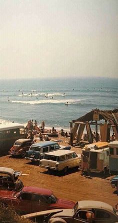 many cars parked on the beach next to the ocean