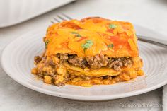 a white plate topped with lasagna covered in meat and cheese next to a fork