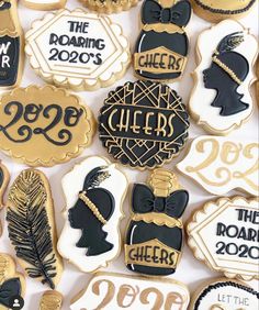 decorated cookies with black and gold accents are displayed on a white tablecloth for the new year's eve celebration