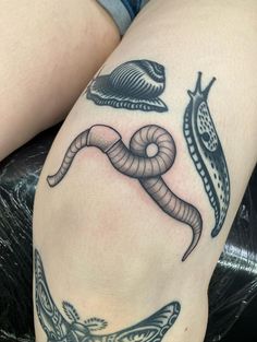 a woman's leg with tattoos on it, including a snake and a snail