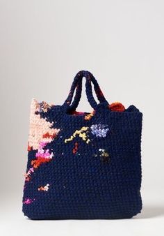 a blue bag with colorful flowers on the handle and handles, sitting against a white background