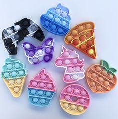 six plastic ice cream molds with sunglasses and fruit shapes on them, all in different colors