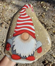 a hand painted rock with a gnome on it's face and a red hat