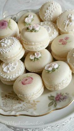 a plate full of white macaroons with pink flowers on them and lace trim around the edges