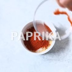 someone is stirring spices in a small white bowl on a counter top with the word paprika over it