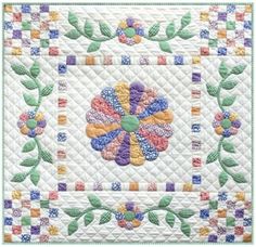 a quilted wall hanging with flowers and leaves on the front, in pastel colors