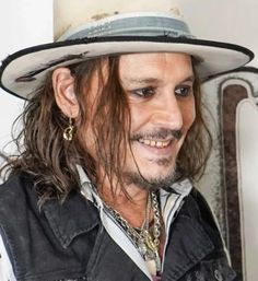 a close up of a person wearing a hat with long hair and a moustache