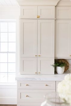 a kitchen with white cabinets and marble counter tops